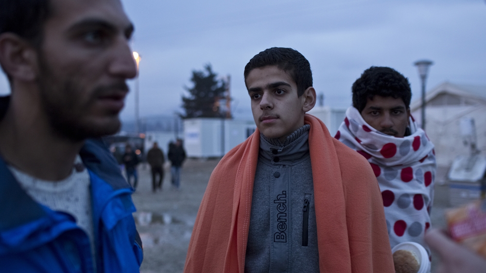 A young Iranian refugee, denied passage into Macedonia, warms up with a blanket while contemplating the situation in Idomeni, Greece [Anna Psaroudakis/Al Jazeera]