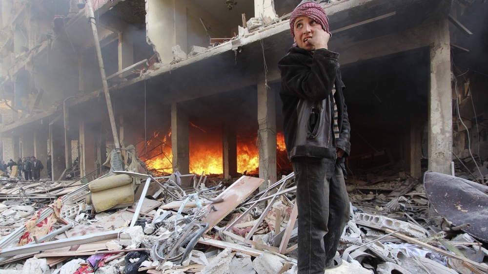 A boy stands on rubble as people try to put out a fire after what activists said were airstrikes and shelling by forces loyal to Syria''s President Assad in Douma