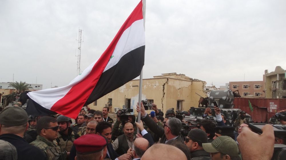 Iraqi Prime Minister Haider al-Abadi holds an Iraqi flag in the city of Ramadi