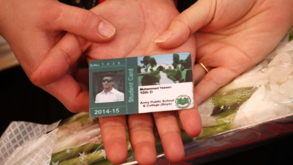 A mother holds a student card of her son during a ceremony on first anniversary of the Peshawar school attack [EPA]