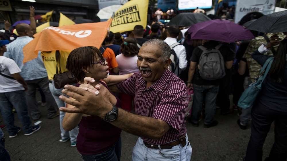 A couple dances during an opposition rally in Caracas [Alejandro Cegarra/Al Jazeera]