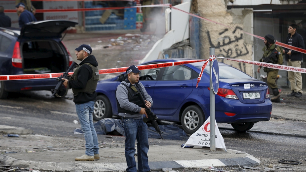 Israeli policemen secure the area near the body of a Palestinian, killed by the military after they said there had been a shooting attack, at an Israeli checkpoint near Hizma
