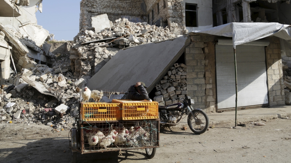 A street vendor sells chicken in front of damaged buildings in the rebel-controlled area of Maaret al-Numan town in Idlib province, Syria