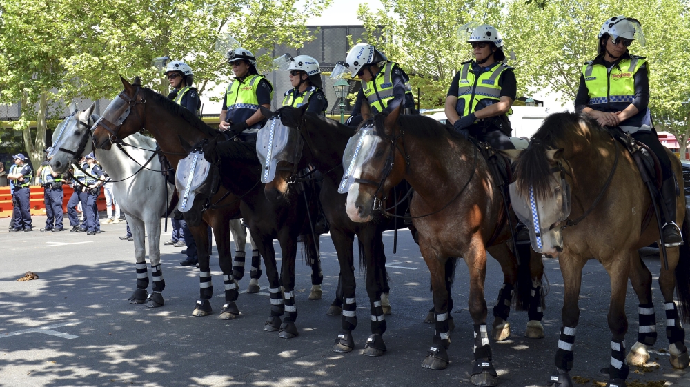 Police sit atop horses and stand guard as they watch members of the left-wing coalition and right-wing activists from the United Patriots Front in the town of Bendigo, located in the st