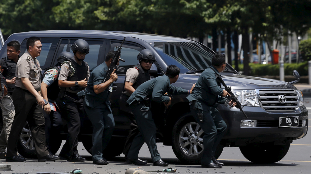 Police officers react near the site of a blast in Jakarta,