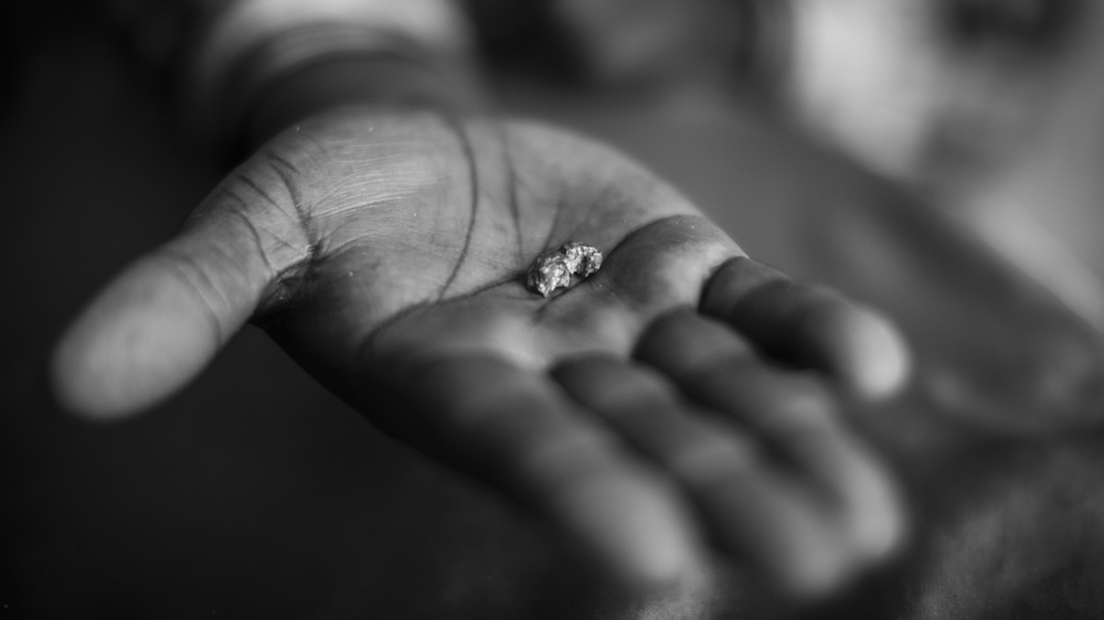 A mineral trafficker displays a gold nugget [Alberto Rojas/Al Jazeera] 