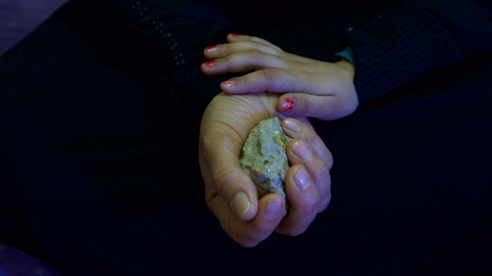 Muntaha keeps a piece of concrete to remind her of her home in Deraa, Syria [Priyanka Gupta/Al Jazeera]