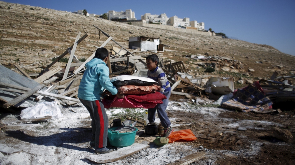 Palestinian boys carry their belongings after the Israeli army demolished their shanty, that their family lives in, near the Israeli West Bank settlement of Maale Adumim, near Jerusalem