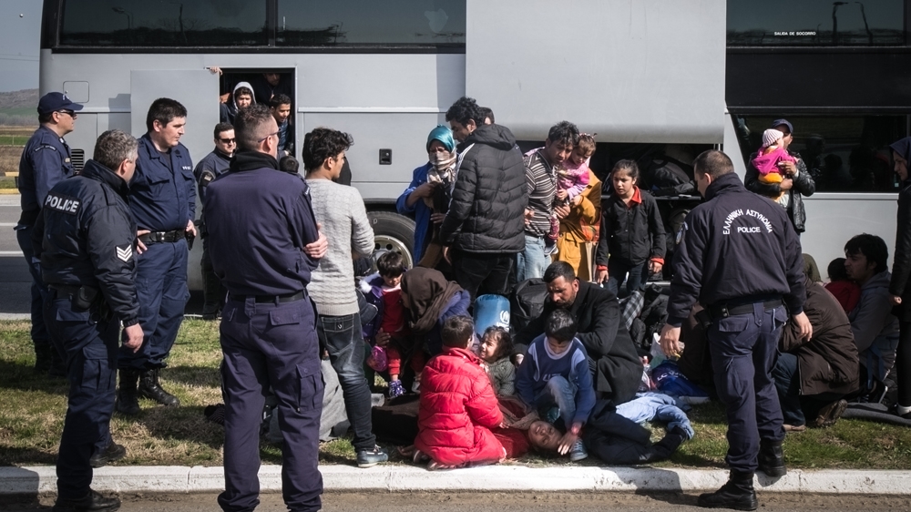 An Afghani woman faints after the police force some of her group to get on a bus to Athens [Nicola Zolin/Al Jazeera] 
