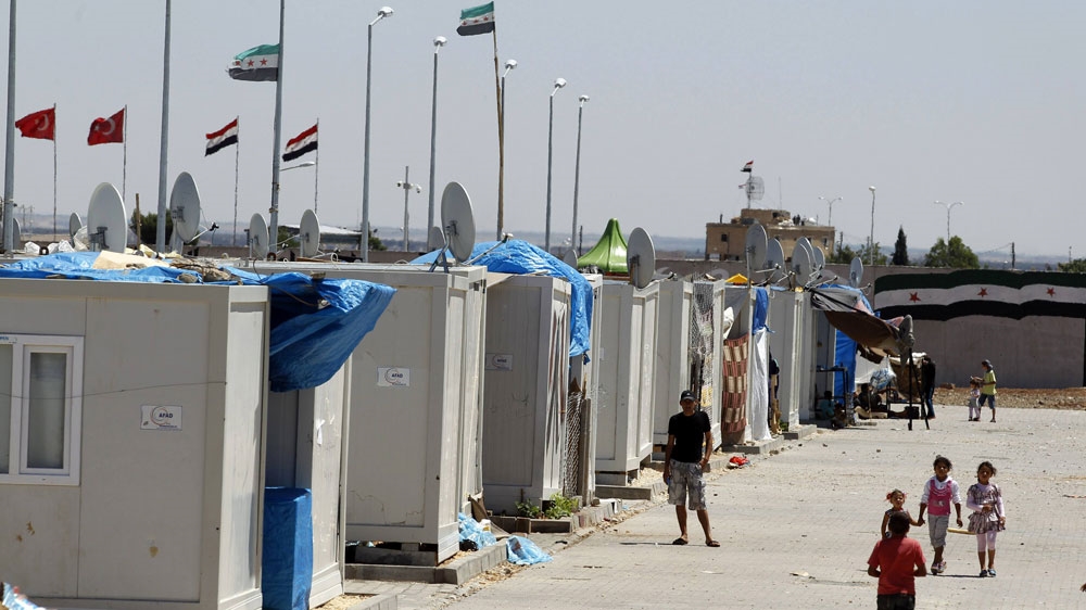 Syrian refugees stroll at a refugee camp named "Container City" on the Turkish-Syrian border