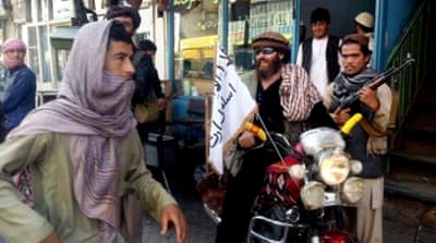 A Taliban fighter sits on his motorcycle adorned with a Taliban flag on a street in Kunduz, Afghanistan [AP]