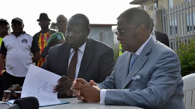 Samuel Akorimo, left, from the UN, signs an extradition order with DRC's Justice Minister Alexis Thambwe Mwamba [Habibou Bangre/Al Jazeera]