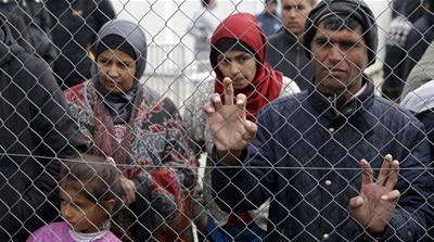 Migrants and refugees stand by a fence at a makeshift camp at the Greek-Macedonian border near the village of Idomeni