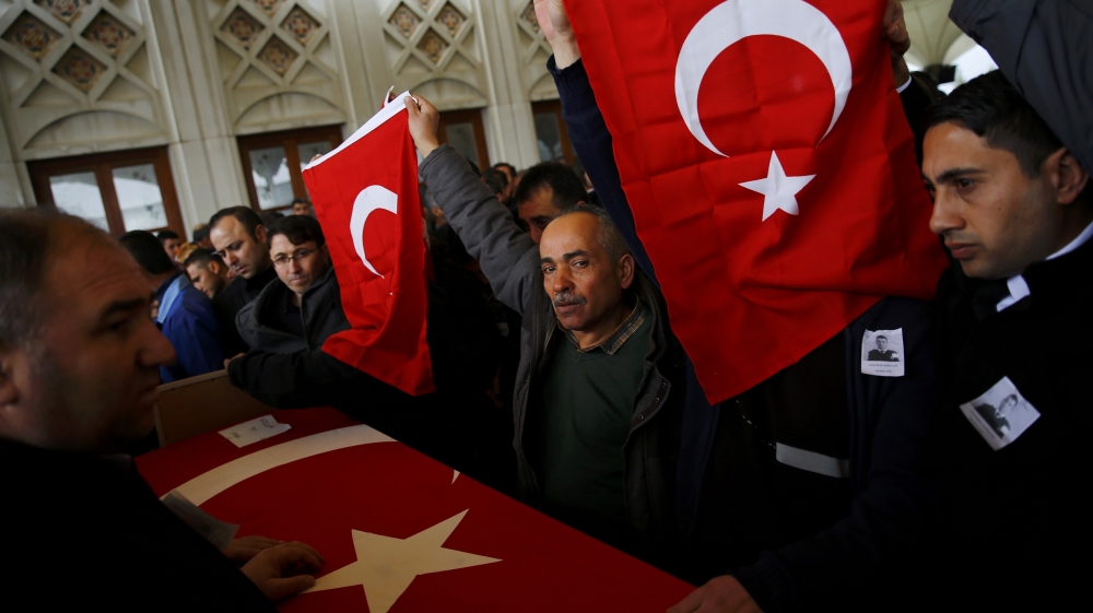Men hold Turkish flags over the coffin of a car bombing victim
