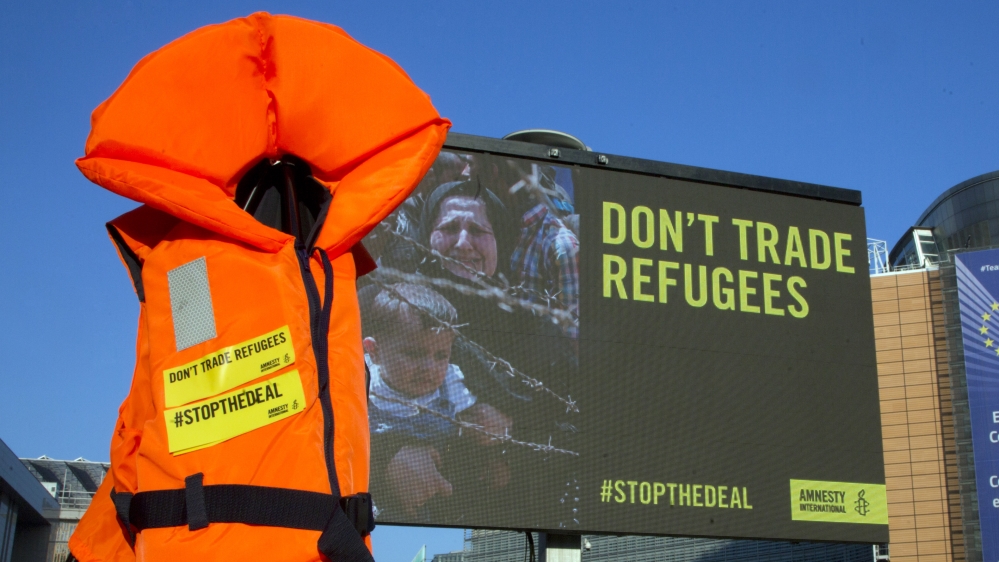 A life jacket hangs next to a giant screen during a demonstration outside EU headquarters in Brussels