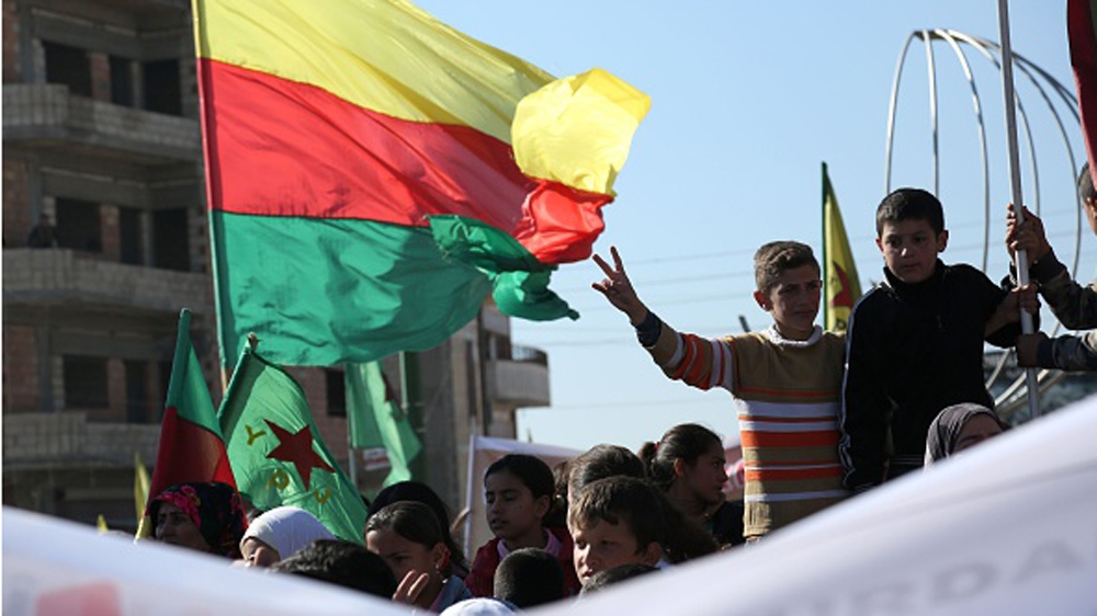 Kurdish children flash the sign for victory next to a flag of the PYD during a demonstration against the exclusion of Syrian-Kurds from the Geneva talks in the northeastern Syrian city of Qamishli [G