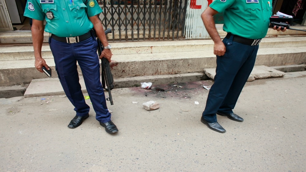 Bangladeshi police officers investigate at the site where unknown assailants hacked student activist Nazimuddin Samad,