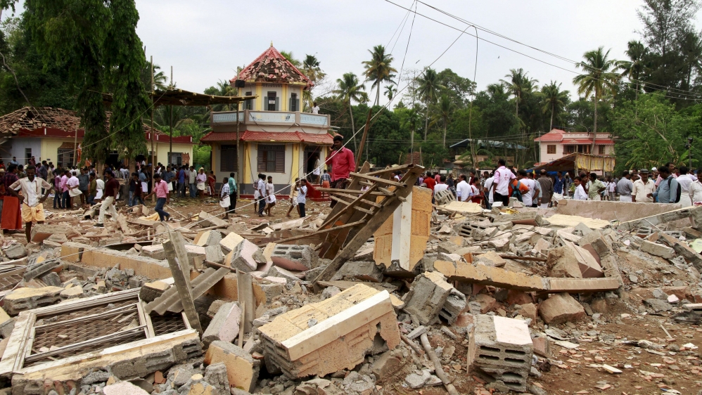 People walk past debris after a fire broke out at a temple in Kollam in the southern state of Kerala [Sivaram V/Reuters]