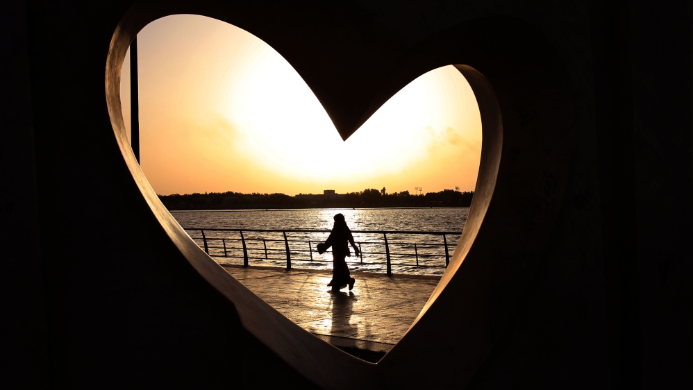 A Saudi woman seen through a heart-shaped statue walks along an inlet of the Red Sea in Jeddah, Saudi Arabia [AP]