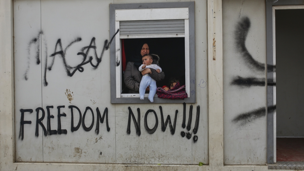 A woman with a child looks out from a container at a makeshift camp for migrants and refugees at the Greek-Macedonian border, near the village of Idomeni