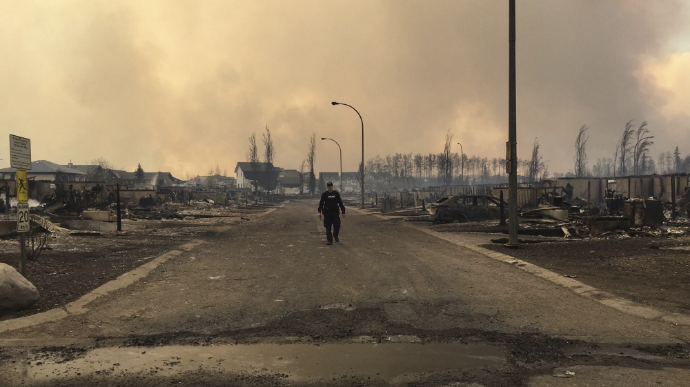 A government worker surveys the damage on a street in Fort McMurray [Alberta RCMP/Reuters]