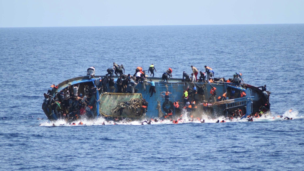 DO NOT USE - Migrants are seen on a capsizing boat before a rescue operation by Italian navy ships "Bettica" and "Bergamini" (unseen) off the coast of Libya