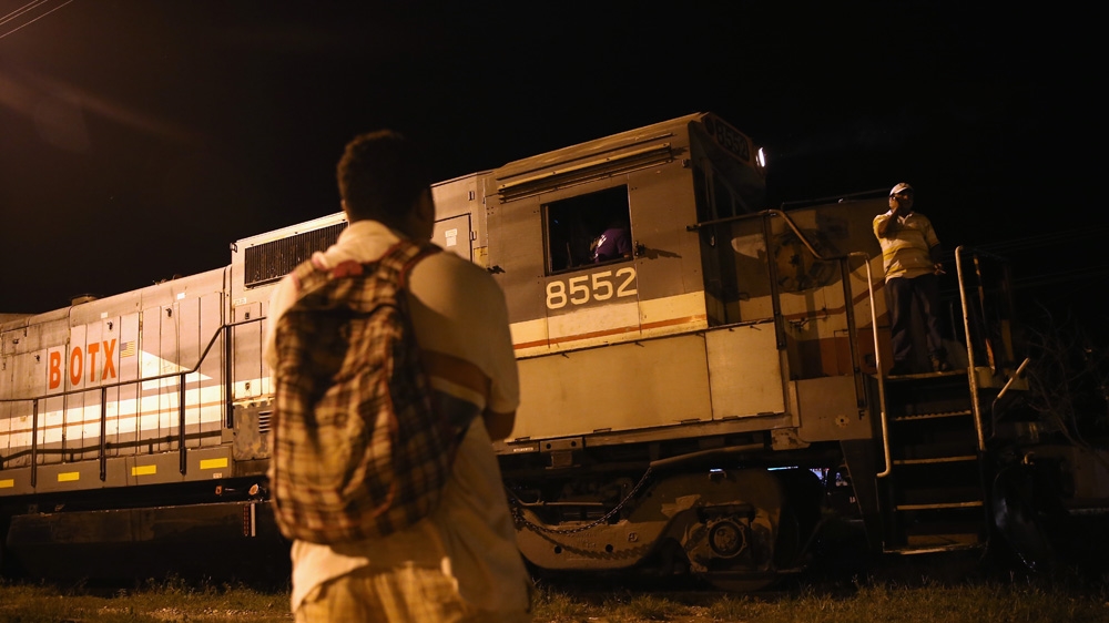 A Central American watches as a freight train arrives in Tenosique, Mexico. Many migrants have perished riding atop