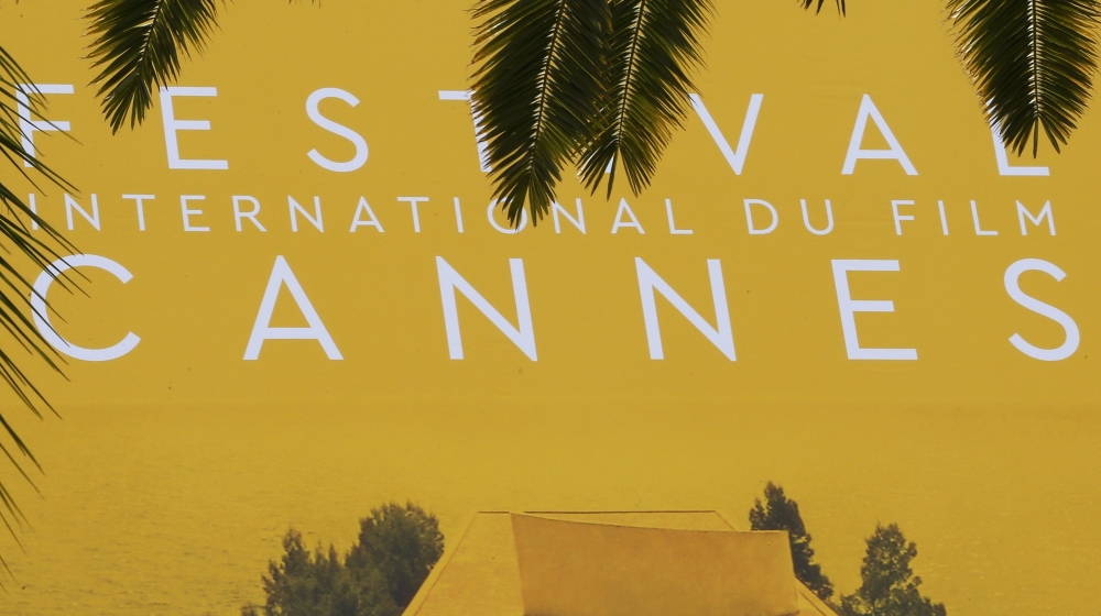 Palm fronds frame a giant canvas of the official poster of the 69th Cannes Film Festival in Cannes, France [REUTERS]