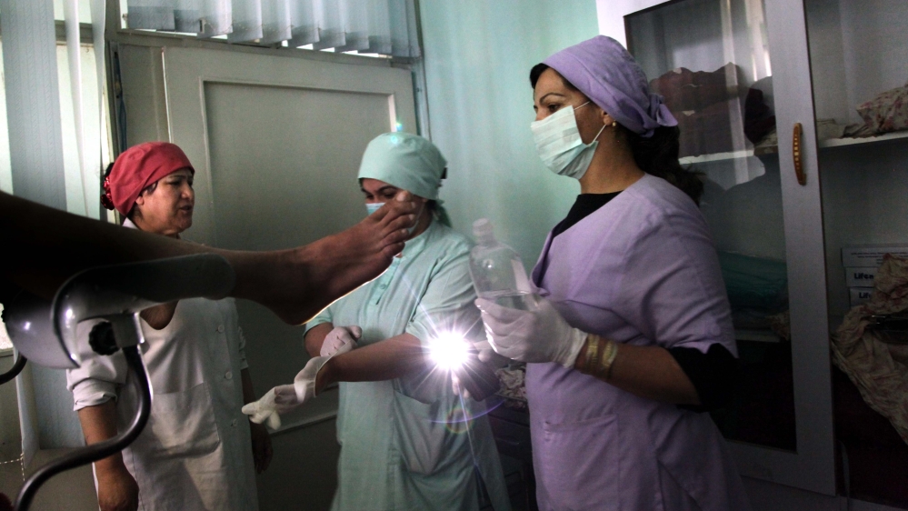 Nafiza performs a consultation; power cuts at the hospital mean the doctors sometimes resort to using their mobile phone lights for consultations [Mariam Alimi/Al Jazeera]