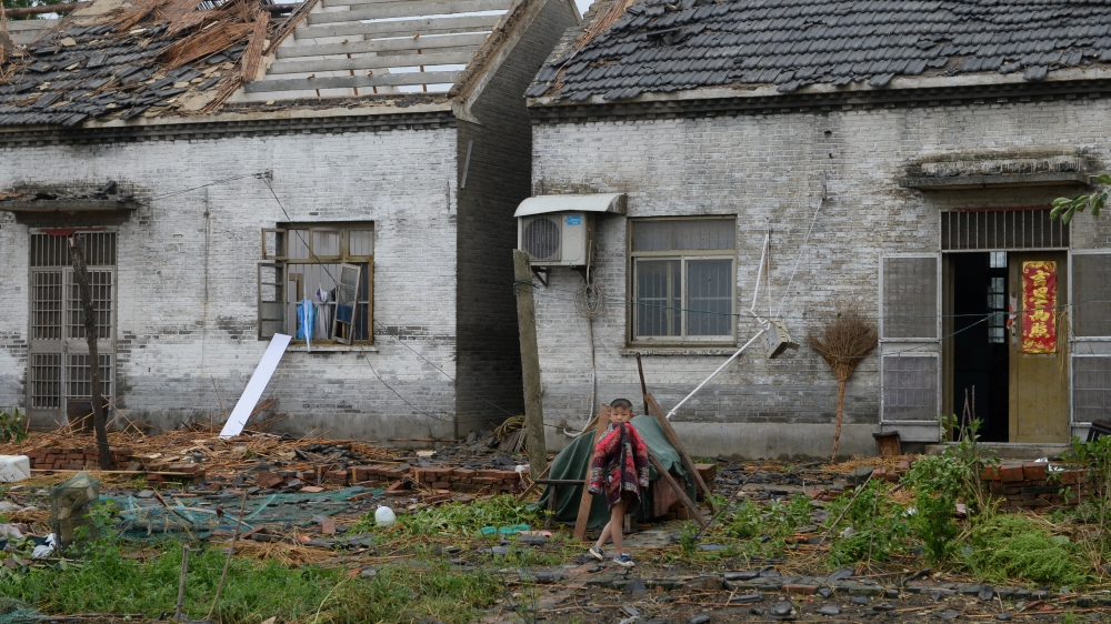 A child walks in front of damaged houses after a tornado hit Yancheng