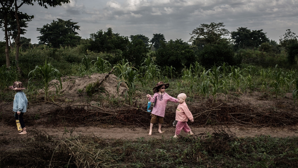 Mwanje, Semabulia and Sekiringa on their way to the local school about five minutes walk through the village [Fredrik Lerneryd/Al Jazeera]