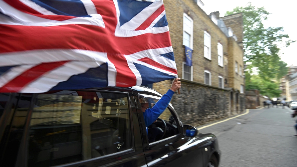 A taxi driver holds a Union flag, as he celebrates following the result of the EU referendum, in central London