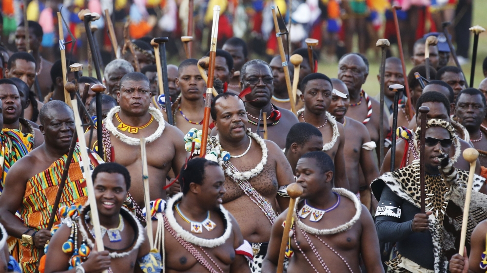 King Mswati III, centre, during the annual ceremony in which female virgins cut reeds and present them to the queen mother. The ceremony provides the king with an opportunity to choose a new wife. [Siphiwe Sibeko/Reuters]