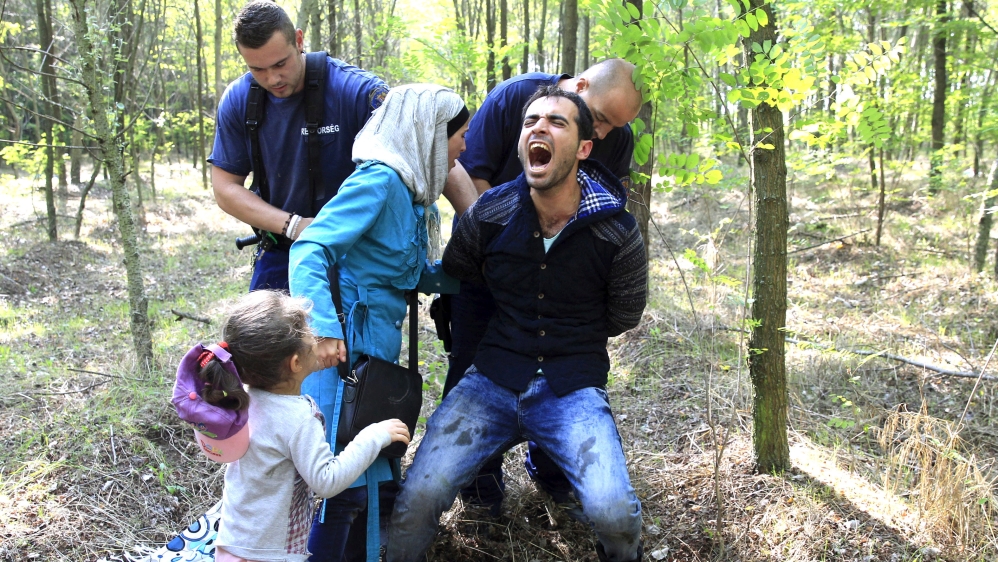 Hungarian policemen detain a Syrian migrant family after they entered Hungary at the border with Serbia, near Roszke