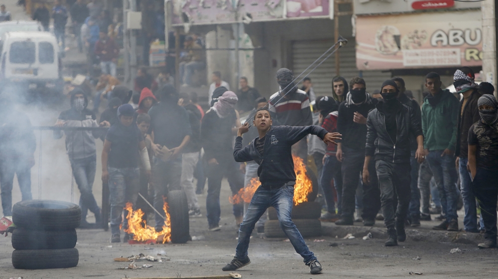 Palestinian protester uses a sling to hurl stones at Israeli troops