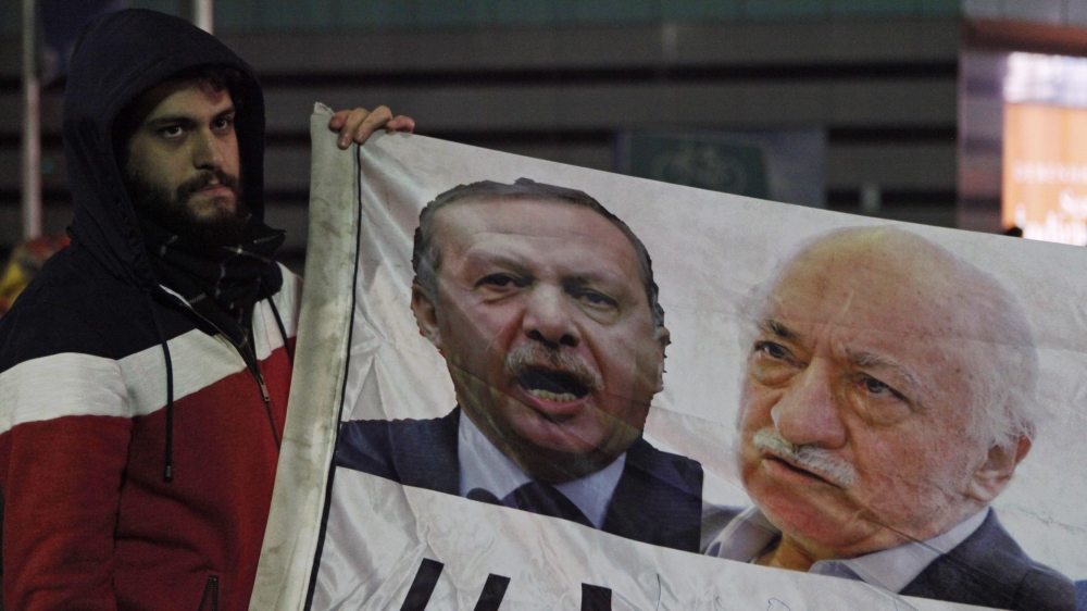 A demonstrator hold pictures of Turkey''s PM Erdogan and Turkish cleric Gulen, during a protest in Istanbul