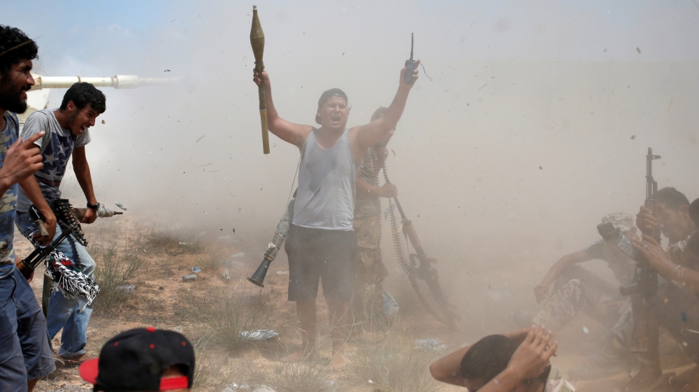 A fighter of Libyan forces allied with the U.N.-backed government gestures after other fighters fire artillery at Islamic State fighters during a battle in Sirte