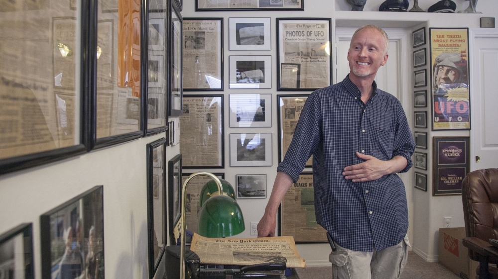 David Marler in his study, where the walls are covered with original newspaper headlines from various UFO events, many of them in New Mexico [Gabriela Campos/Al Jazeera]