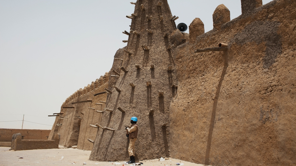 A UN peacekeeper in Timbuktu stands guard at the Djinguereber mosque, built in the 14th century [File: Joe Penney/Reuters]