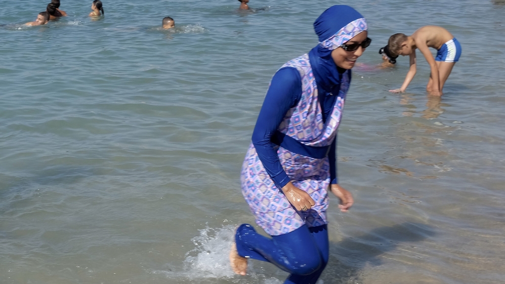 A woman wearing a burkini walks in the water on a beach in Marseille