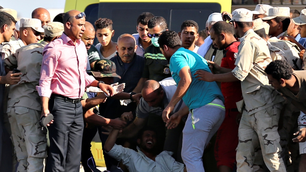 A man reacts as rescue workers carry the body of a victim on a stretcher after a boat carrying migrants capsized off Egypt''s coast, in Al-Beheira
