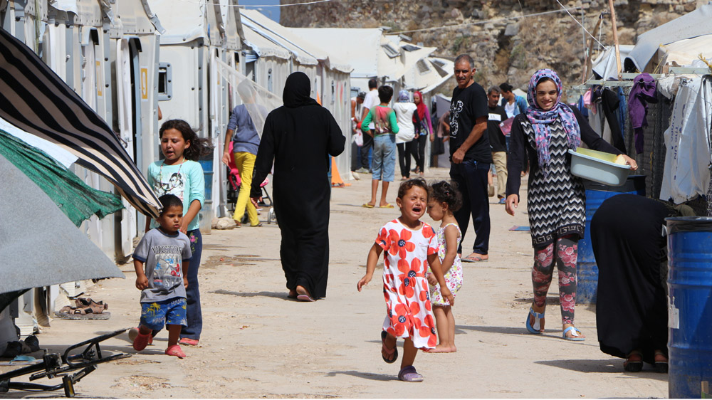  Refugees walk on the main street of the tent city at Souda, outside the Venetian fortress, in Chios town [John Psaropoulos/Al Jazeera]
