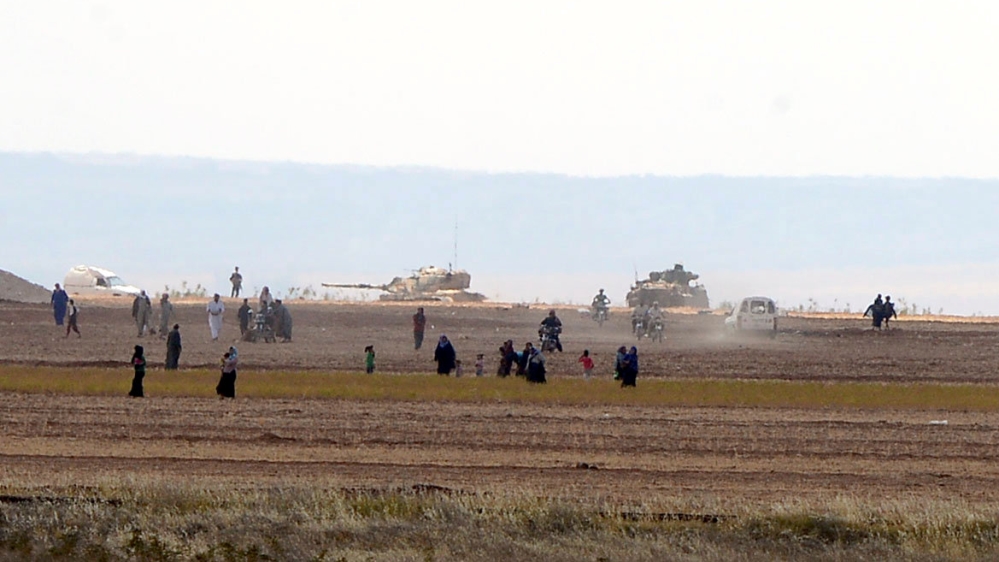 Syrian civilians, with Turkish Army tanks in the background, walk through the Turkish border towards the Turkish town of Killis on September 3, 2016 [Reuters]