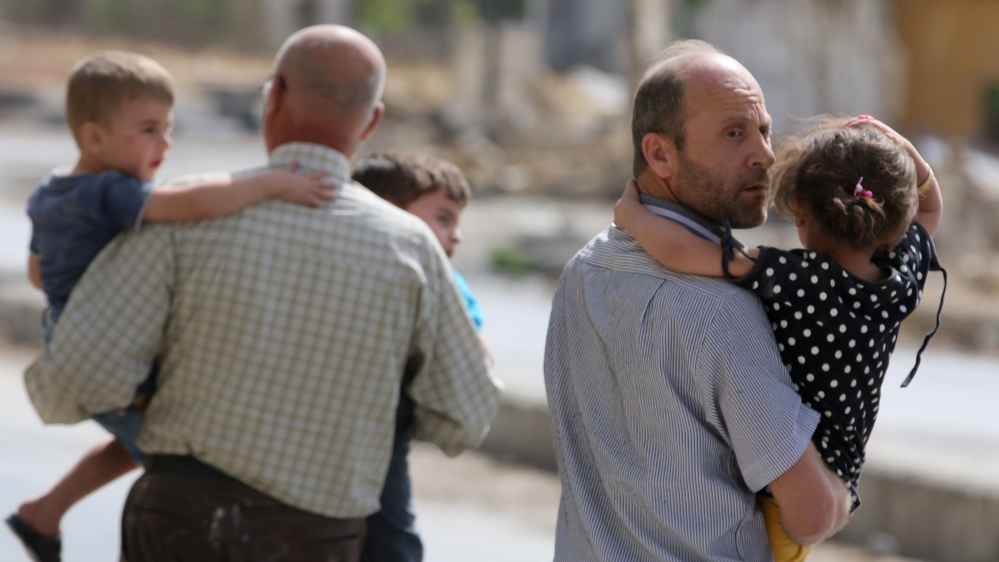 Men carry children away from a damaged site after airstrikes on the rebel held al-Qaterji neighbourhood of Aleppo
