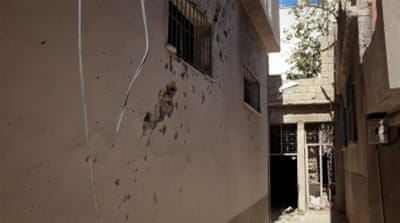 Shrapnel marks can be seen on the exterior wall of Saoud Faour's clothing shop [Megan O'Toole/Al Jazeera]