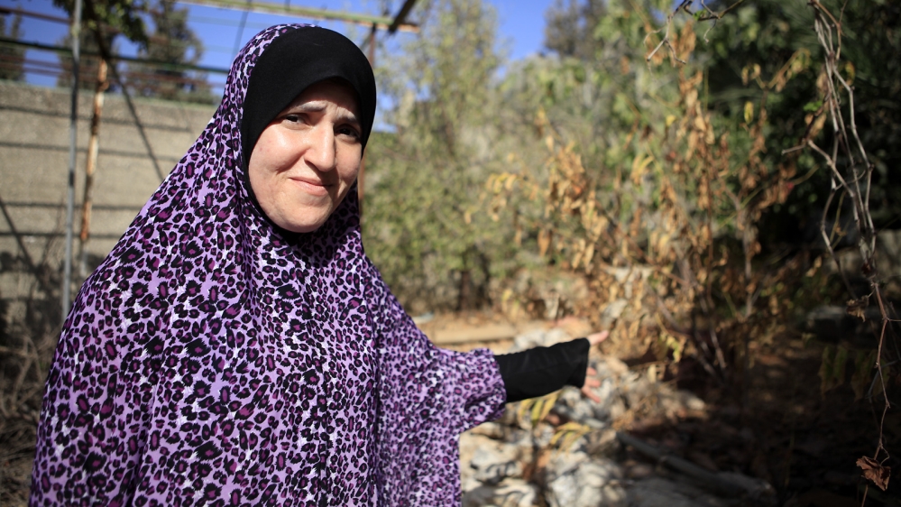 Enas Taha shows her garden, which has turned brown due to the severe water shortages since June [Eloise Bollack/Al Jazeera]