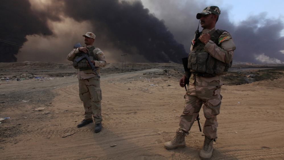 Iraqi army members stand with thier weapons in Qayyarah