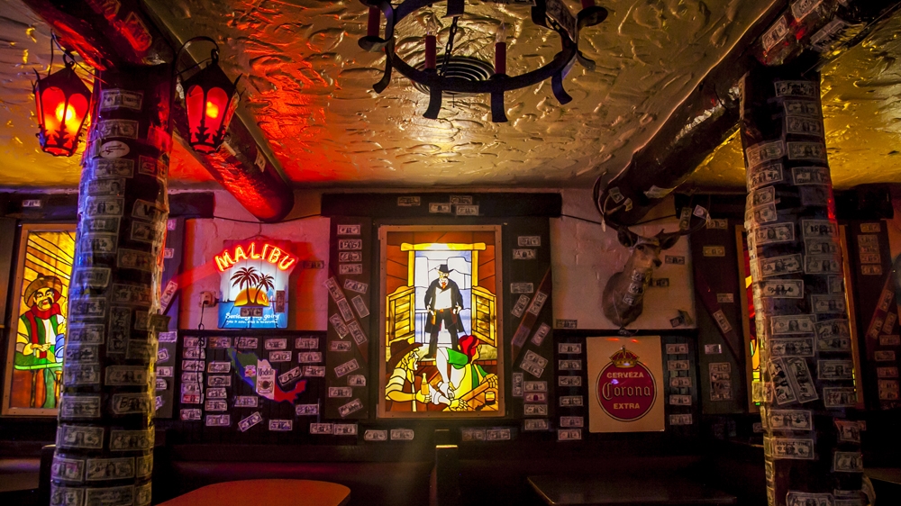 Stained glass and dollar bills decorate the walls of the El Rancho bar in Gallup New Mexico [Gabriela Campos/Al Jazeera]