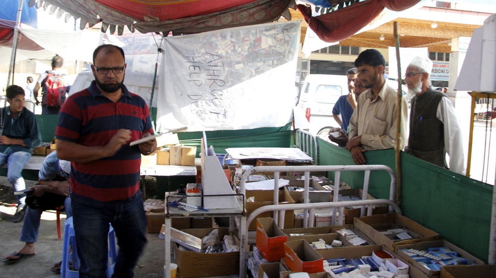 Sajad Ahmad Zaz gives medicine to patients at the Athrout camp in the SMHS compound [Zahid Rafiq/Al Jazeera]