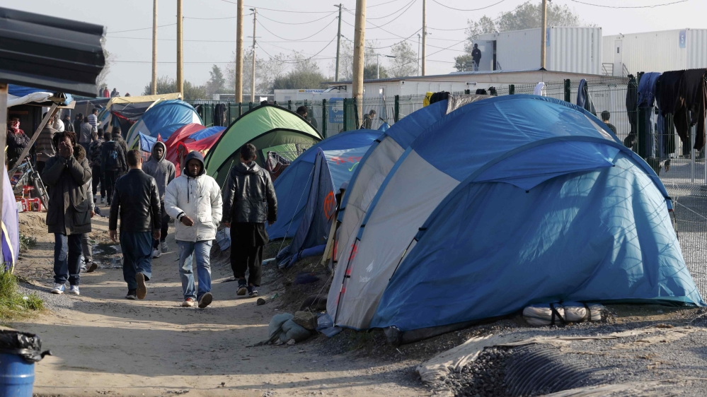 Migrants walk in an alley near tents and makeshift shelters on the eve of the evacuation and dismantlement of the camp called the "Jungle" in Calais